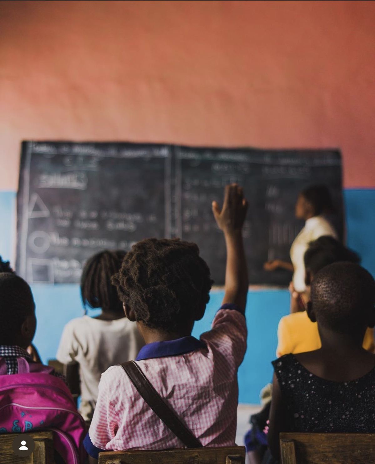 Children in a classroom raising hands